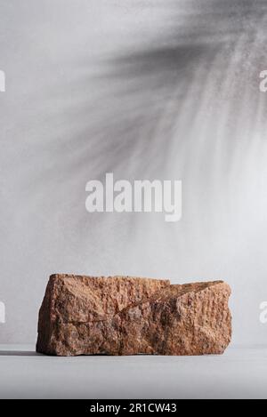 Produktdisplay mit grauer Betonstruktur und Steinpodium mit Handfläche hinterlässt Schatten auf dem Hintergrund. Natürliches Schönheitssockel bei Sonnenlicht. Stockfoto