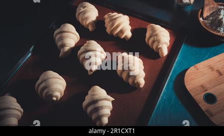 Der Koch schmiert das Eigelb mit wunderschönen Käse-Croissants, bevor er in den Ofen geht Stockfoto