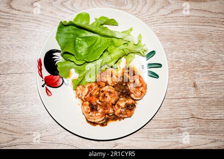 Meeresfrüchte-Gericht scharfe gebratene Garnelen. Meeresfrüchte im Süden Thailands. Garnelen und Gemüse liegen auf einem Teller auf einem Holztisch. Selektiver Fokus. Nahaufnahme und CO Stockfoto