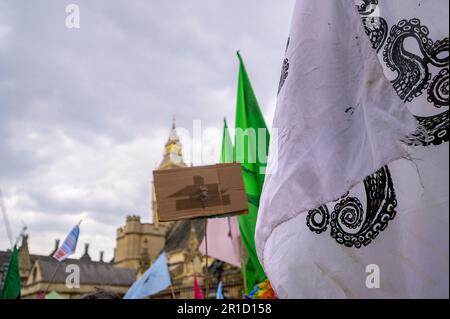 LONDON - 22. April 2023: Erleben Sie den mächtigen Anblick des Aussterbens Rebellion-Flaggen über Demonstranten beim XR-marsch in der Nähe der Houses of Parliament in Lo Stockfoto