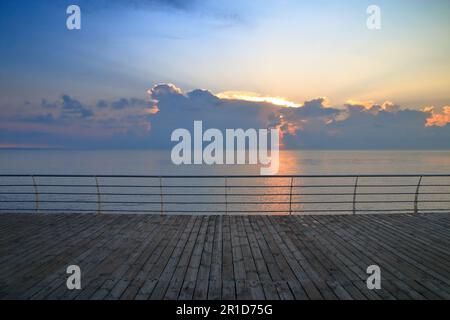 Das Foto wurde an der Küste der Stadt Odessa in der Ukraine gemacht. Das Bild zeigt die hölzerne Terrasse des Ufers bei Sonnenaufgang auf dem Meer. Stockfoto