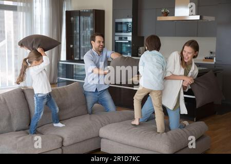 Energiegeladene kleine Kinder und fröhliche Eltern, die aktive Spiele spielen Stockfoto