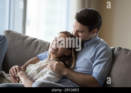 Fröhliches Paar, das sich verliebt hat und auf der bequemen Couch ruht Stockfoto