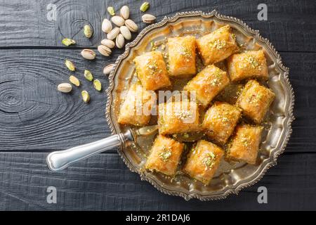 Schichtige, süße Pistazienbaklava mit Honig Nahaufnahme auf einem Teller auf dem Tisch. Horizontale Draufsicht von oben Stockfoto