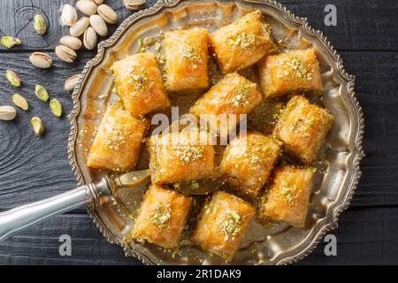 Türkisches traditionelles köstliches Baklava mit Pistazien auf dunklem Holzhintergrund. Horizontale Draufsicht von oben Stockfoto