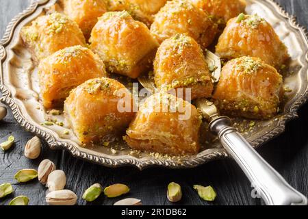 Traditionelles türkisches Dessert mit Pistazien-Baklava und Honig aus nächster Nähe auf einem Teller auf dem Tisch. Horizontal Stockfoto