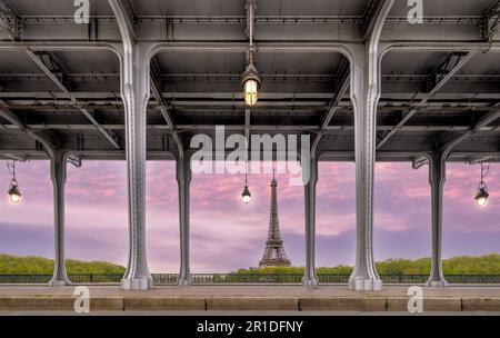 Eiffelturm, der durch die Stahlstützen der Bir-Hakeim-Brücke in Paris gerahmt ist und einen ikonischen architektonischen Stadtblick erzeugt. Stockfoto
