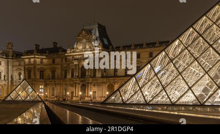 Der Louvre in Paris, Frankreich. Glaspyramiden bei Nacht im berühmten Museum. Stockfoto