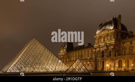 Der Louvre in Paris, Frankreich. Glaspyramiden bei Nacht im berühmten Museum. Stockfoto