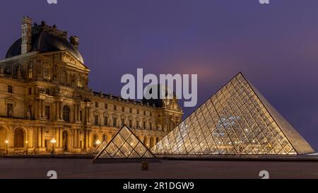 Der Louvre in Paris, Frankreich. Glaspyramiden bei Nacht im berühmten Museum. Stockfoto