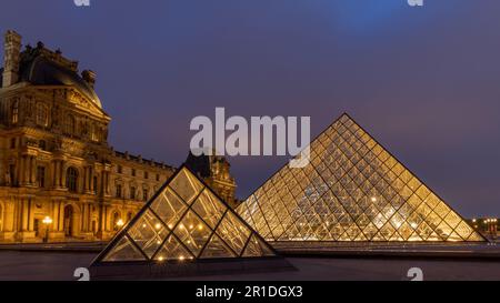 Der Louvre in Paris, Frankreich. Glaspyramiden bei Nacht im berühmten Museum. Stockfoto