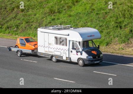 2003 Auto-Trail Ducato 15 LWB TD Carioca Motorheim, Abschleppen 1970 70s Orange Bond Bug 700ES 850cc Benzin Konzeptfahrzeug. Wohnmobile auf den Straßen Großbritanniens, Wohnmobil Freizeitfahrzeug, Familienurlaub, Caravanettenurlaub, Touring Caravan Urlaub, Umbauten von Kleinbussen;Reisen auf der Autobahn M61, Manchester, Großbritannien Stockfoto