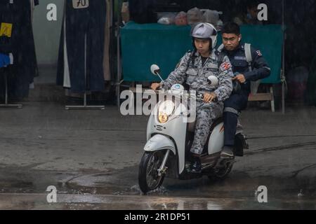 SAMUT PRAKAN, THAILAND, MAI 10 2023, Männer in Militäruniformen fahren Motorrad im Regen Stockfoto