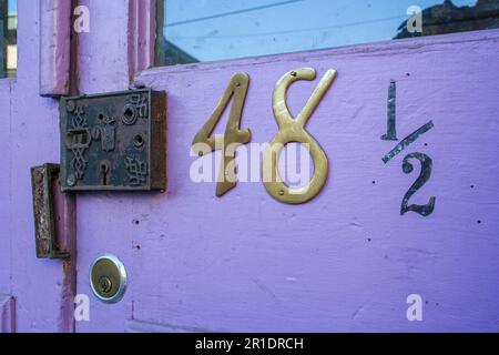 Lilavendelfarbene Tür mit Glas und Nummer 48 und ein altes Schloss. Gefunden in Eureka Springs, Arkansas. Stockfoto