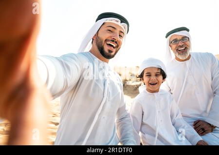 Drei Generationen Familie machen eine Safari in der Wüste von Dubai in weißem Kandura-Outfit. Großvater, Sohn und Enkel verbringen Zeit zusammen im Jahr Stockfoto