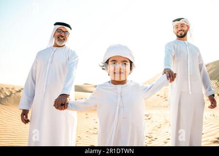 Drei Generationen Familie machen eine Safari in der Wüste von Dubai in weißem Kandura-Outfit. Großvater, Sohn und Enkel verbringen Zeit zusammen im Jahr Stockfoto