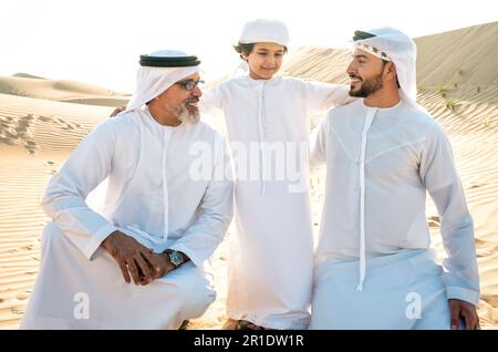 Drei Generationen Familie machen eine Safari in der Wüste von Dubai in weißem Kandura-Outfit. Großvater, Sohn und Enkel verbringen Zeit zusammen im Jahr Stockfoto