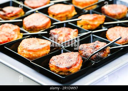 fingerfood-Nahaufnahme. Kleine orientalische Snacks auf quadratischen schwarzen Tellern mit winzigen Löffeln. Catering-Grundriss. Gourmetspeisen. Menü Konzept Stockfoto