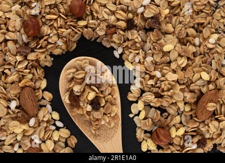 Hausgemachtes Müsli auf schwarzem Hintergrund, gesundes Frühstück mit Haferbrei Müsli, Nüssen, Samen und getrockneten Früchten. Draufsicht. Stockfoto