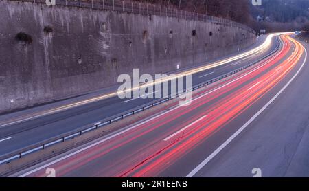 Helle Spur weißer Scheinwerfer und roter Hinterleuchtung von Autos auf der Autobahn, die mit Langzeitbelichtung aufgenommen wurden. Verkehrs- und Geschwindigkeitsthema Stockfoto