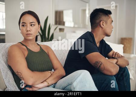 Sie sitzen still. Ein junges Paar, das sich nach einem Streit zu Hause ignoriert. Stockfoto