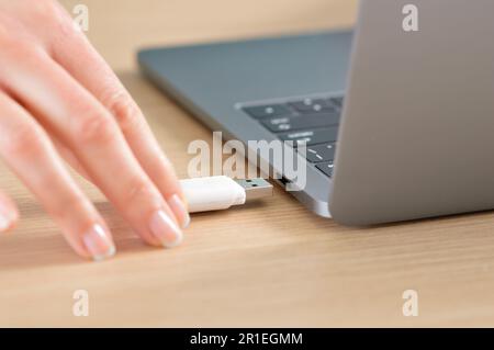 Nahaufnahme einer Frau hand Anschluss ein USB-Stick in einem Laptop auf einem Desktop Stockfoto