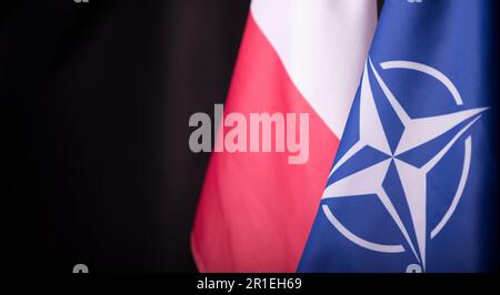Ukraine, Kiew - 10.04.2023. Offizielle Flaggen Polens und der NATO vor schwarzem Hintergrund. Ein Symbol der Einheit und Widerstandsfähigkeit in einer Welt der Unsicherheit und Stockfoto