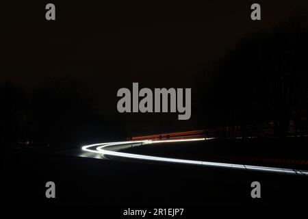 Lange Belichtung von Autolichtern auf einer kurvenreichen Autobahn bei Nacht Stockfoto
