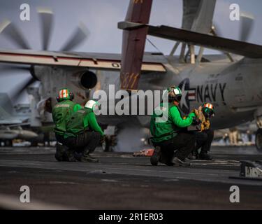 230513-N-MH015-1227 PHILIPPINE SEA (13. MAI 2023) USA Marinesachverständige beobachten, wie ein E-2C Hawkeye von den ‚Sun Kings‘ der Flugzeugträger-Frühwarnstaffel (VAW) 116 vom Cockpit des Flugzeugträgers USS Nimitz (CVN 68) startet. Nimitz ist in der US-7.-Flotte und führt Routineeinsätze durch. 7. Fleet sind die USA Die größte Flotte der Navy, die mit einer Anzahl von Flotten ausgestattet ist, interagiert und arbeitet regelmäßig mit Verbündeten und Partnern zusammen, um eine freie und offene Region im Indo-Pazifik zu erhalten. (USA Marinefoto von Mass Communication Specialist 2. Klasse Joseph Calabrese) Stockfoto