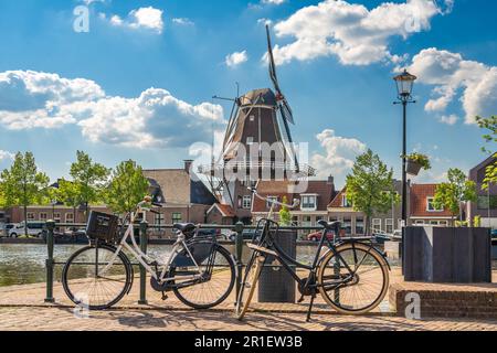 Eine typisch holländische Szene mit traditioneller Windmühle und Fahrrädern entlang des Kanals in der Stadt Meppel an einem sonnigen Frühlingstag Stockfoto