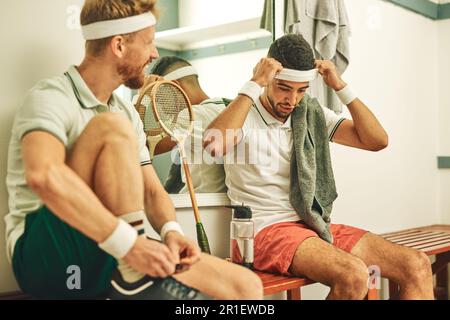 Der Countdown, um den Wahnsinn zu zerquetschen. Zwei junge Männer ziehen sich nach einem Squash-Spiel in der Umkleide an. Stockfoto