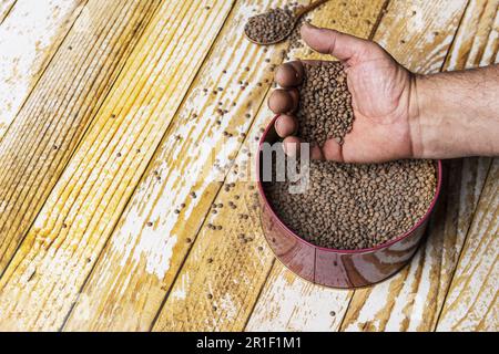 Eine Hand, die durch eine Metallbox voller getrockneter Linsen geht Stockfoto