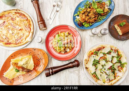 Ein Set italienischer Gerichte mit viel Pasta, Parmesankäse und verschiedenen Pizzen Stockfoto