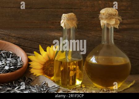 Flaschen mit Sonnenblumenöl, Samen und Blumen auf dem Tisch Stockfoto