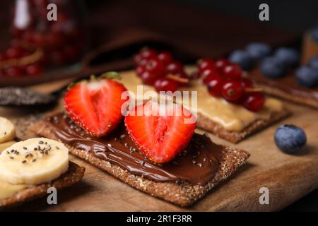 Frisches knuspriges Roggen-Knusperbrot mit verschiedenen Belägen auf Holzbrett, Nahaufnahme Stockfoto