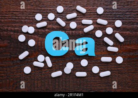 Papiersymbol Ca (Calcium) und Pillen auf Holztisch, Draufsicht Stockfoto
