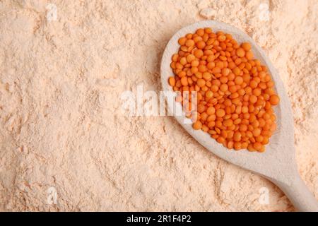 Löffel mit Linsenkörnern auf Mehl, Draufsicht. Platz für Text Stockfoto