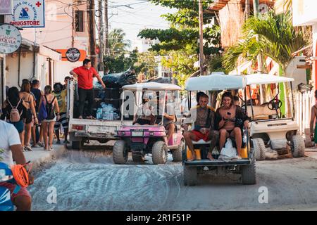 Touristen fahren mit einem Golfwagen durch schlammige Straßen von Isla Holbox, Mexiko Stockfoto