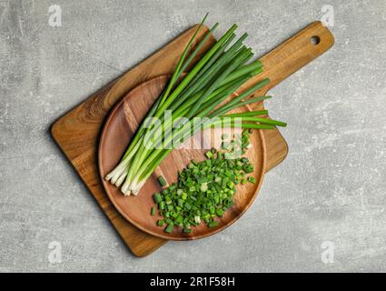 Gehackte grüne Frühlingszwiebel und Stiele auf grauem Tisch, Draufsicht Stockfoto