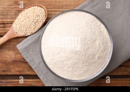 Quinoamehl in Keramikschüssel und Löffel mit Samen auf Holztisch, flach liegend Stockfoto