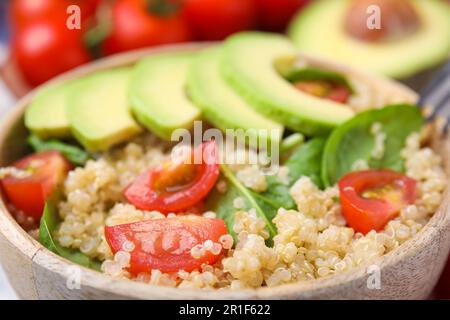 Köstlicher Quinoa-Salat mit Tomaten, Avocado-Scheiben und Spinatblättern, Nahaufnahme Stockfoto