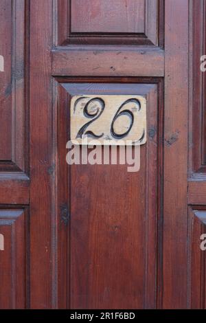 Nummernschild mit Hausnummer 26 auf Holztür, schließen Stockfoto