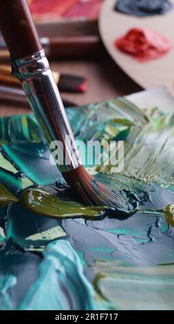 Pinsel auf der Leinwand des Künstlers mit gemischten Farben, Nahaufnahme Stockfoto