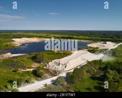 Riesiger Hügel mit Flusssand in der Nähe eines Teiches in offenem Steinbruch Stockfoto