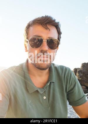 Porträt eines jungen Mannes mit Sonnenbrille am Meer Stockfoto