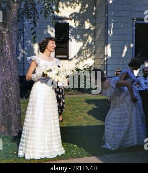 Eine Frau im Hochzeitskleid und eine Brautjungfer oder ein Blumenmädchen, die mit ihrem (r) Ca. 1950-1955 Stockfoto