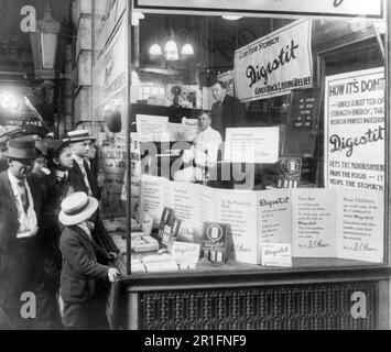 Archivfoto: Käufer, die auf die Schaufensterausstellung von Brown's Drug Store schauen, werben für „Digestit“, ein Patentarzneimittel zur Magenentlastung; das Produkt wird von einem Pianisten, „Mr. Thomas“, empfohlen, der seit 60 Stunden und 45 Minuten ununterbrochen im Schaufenster spielt. 1915 Stockfoto