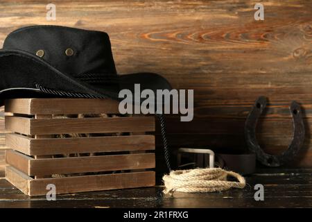 Cowboyhut, Hufeisen und Lasso auf Holzhintergrund Stockfoto