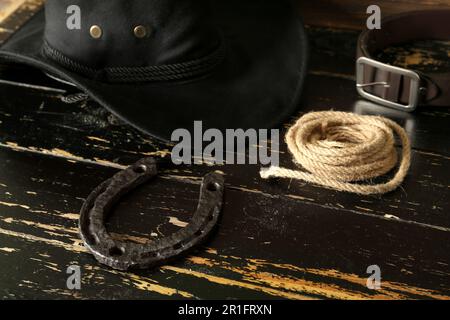 Cowboyhut, Hufeisen und Lasso auf Holzhintergrund Stockfoto