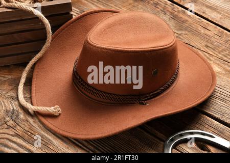 Cowboyhut, Lasso und Hufeisen auf Holzhintergrund Stockfoto